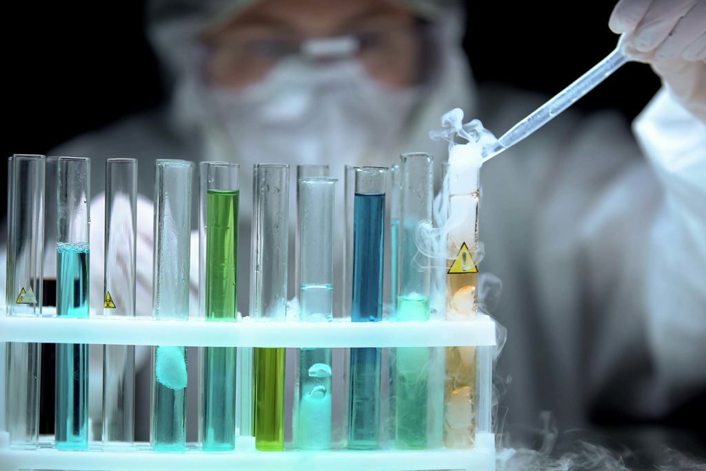 Scientist dropping sample to liquid boiling in test tube with warning symbol